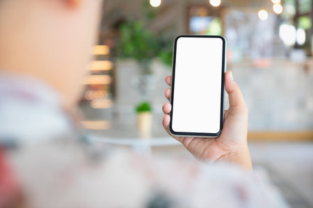 Back view close up of a person using smartphone mockup blank screen in home interior. Mock up white...
