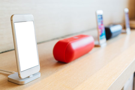 Mockup blank white screen new mobile smartphones with blurred wireless speaker background.