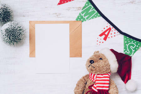 Blank Christmas Card and gold brown envelope with Christmas decorations. Xmas tree models and bear dolls ornaments, top view. Holiday party workspace mock up, postcard with copy space.の写真素材