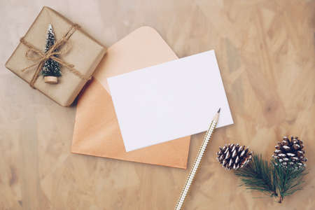 Mockup Blank White Empty Christmas greeting card top view and gift box, flatlay on a wooden background, with place for your text for Merry Christmas and Happy New Year festive background.の写真素材