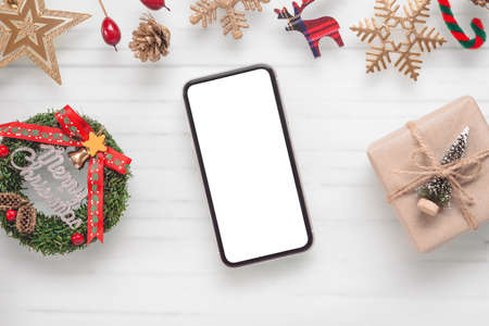 Mockup blank white screen smartphone on white desk background for Christmas, Flat lay top view with copy space for your Merry Christmas artwork.の写真素材