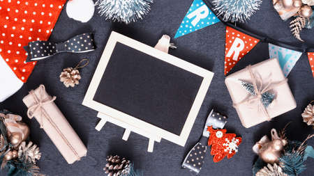 Mockup chalkboard with blank empty screen, new year gift box with Xmas pine tree model, christmas ornaments on wood background, top view, copy space place for your artworkの写真素材