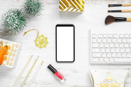 Mockup beauty Christmas New Year concept. Mock up blank empty space smartphone with makeup cosmetic, Christmas decoration ornaments, New Year gifts on grung white desk table background, top view.の写真素材