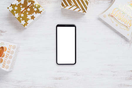 Mockup blank white screen smartphone on white wood background for Christmas and New Year party background, Flat lay top view with copy space for your Merry Christmas and Happy New year artwork.の写真素材