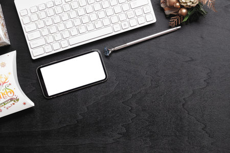 Mockup smartphone with blank white screen, new year gift box with Xmas christmas ornaments on grunge...