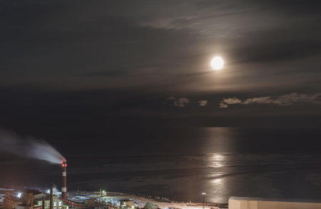 Factory against the sea in the moonlight night landscape moon beach smoking chimneys, fluesの写真素材