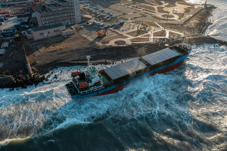 The dry cargo ship washed ashore during a sea storm. Oil spills. An offshore cargo ship washed ashore during a severe storm. A strong sea wind washed ashore a large tanker carrying cargo ran aground.の写真素材