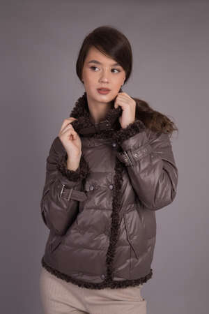 A young girl model posing at the camera demonstrates clothes in different positions.Shooting in a clothes studio on a gray background showing a model.の写真素材