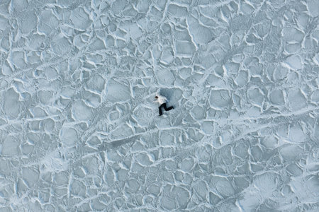 The girl runs on the frozen texture of ice. Sea view from above on sea water ice texture. In winter, the sea froze, turning into an ice field of frozen ice floes. background of frozen ice cubes.の写真素材
