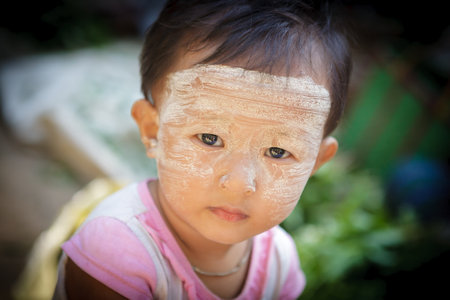 YANGON - MYANMAR - November 15, 2013: Unidentified Burmese boy with thanaka on his face on November 15, 2013 in Yangon, Myanmar. Thanaka is a yellowish-white cosmetic paste made from ground bark.のeditorial素材