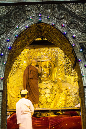 MANDALAY-DECEMBER 8 2013: Monk spray water to Buddha image face in ritual of face wash to Mahamuni Buddha on December 8, 2013 at Mahamuni temple-Mandalay Myanmar.This ritual commences every morning at 4am.のeditorial素材