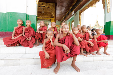 OLD BAGAN, MYANMAR- OCT 15, 2013 : Group of unidentified young novice monks sitting down at Shwedagon Pagoda Temple, Myanmar on October 15, 2013. 89% of the Burmese population is Buddhist.のeditorial素材