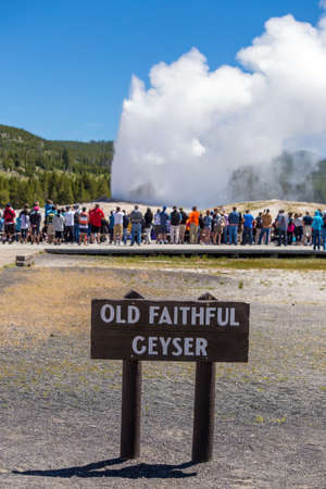 Tourists watching the Old Faithful erupting in Yellowstone National Park, USAの写真素材