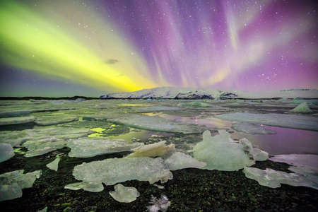 Auroral display over the glacier lagoon Jokulsarlon in Iceland.の写真素材