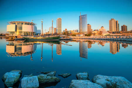 Milwaukee skyline at twilight with city reflection in lake Michigan and harbor pier.の写真素材