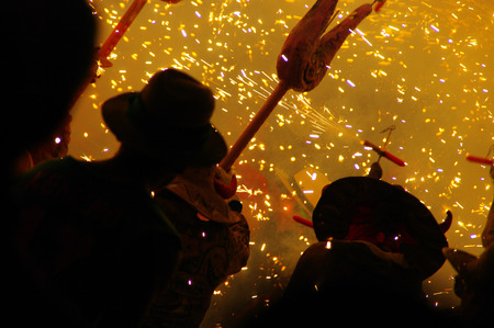 Men disguised as masked devil, with symbology and fireworks in traditional festival
