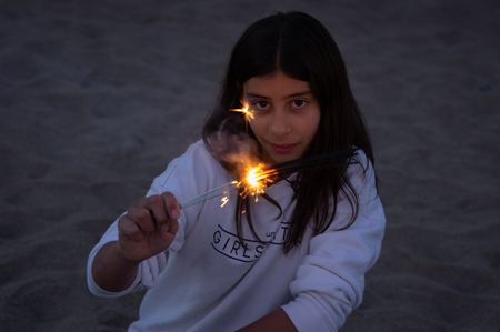 Teenager look during sunset on the beach while holding in his hand some bengalsの写真素材