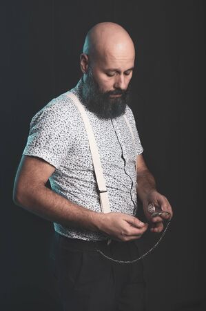 Bearded man looking at pocket watch, studio photography. Hipster, fashion.の写真素材