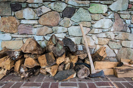 Firewood stocked next to Ax in front of Stone Wall