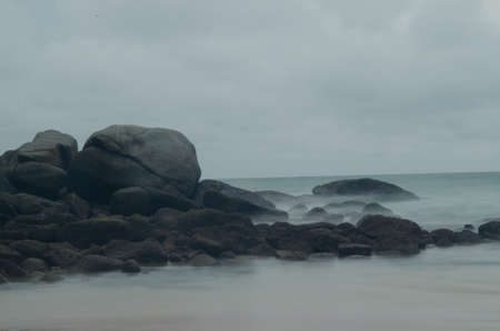 moss on the giant rock with motion of seaの写真素材