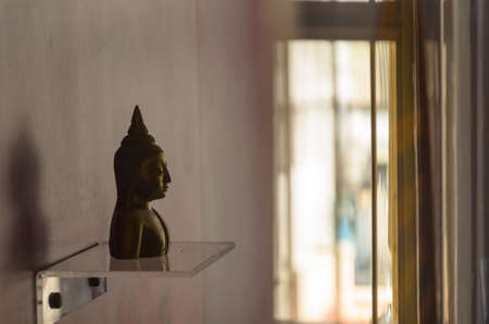 Head of Buddha on the stand reflex the shadow to the wallの写真素材