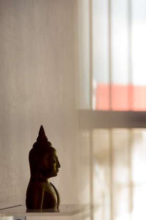 Head of Buddha on the stand reflex the shadow to the wallの写真素材