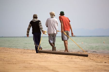 three arab cleaning beachの写真素材