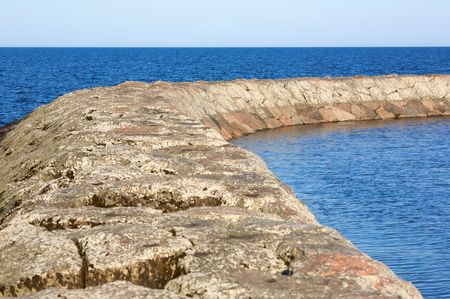 A dividing wall in the ocean made of cement and stone.の写真素材