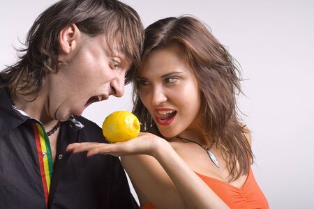 man eats a lemon from a palm of womanの写真素材
