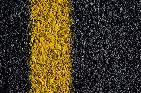 A closeup view of the yellow marking on a asphalt road.