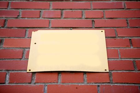 Blank beige sign tacked to a red brick wall.の写真素材
