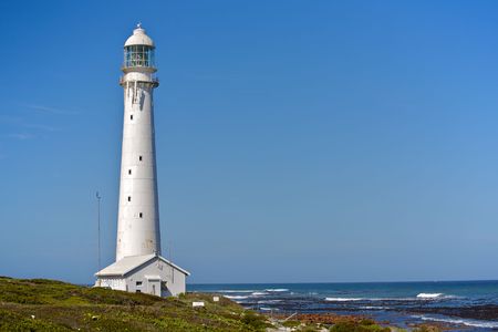 A tall white lighthouse facing the Indian Ocean, on a South African beach.の写真素材