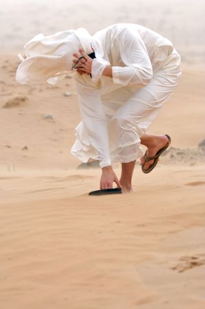 The man in Arab clothing in the desert, with a strong wind dropped headpiece.の写真素材