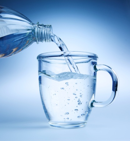Clear blue water being poured into a glass mug. Photos in blue tone.の写真素材