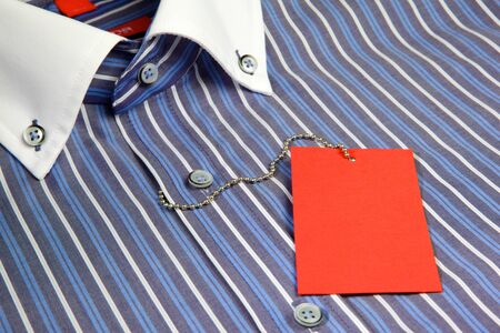 Blue men's shirt with white collar and empty red label on iron ropeの写真素材