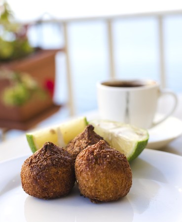 Three small pieces of kebbe, a lebanese dish with mince meat or mushrooms and lemon and coffee on the background  Delicious food  の写真素材