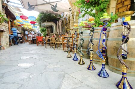 Stoa Fylaktou in the historic medieval city center of Limassol in Cyprus. A view of the cafe, restaurant, the colorful umbrellas hang over the tables, a line of shisha and the old decorated walls.の写真素材