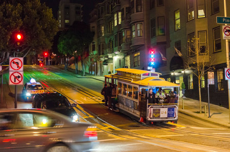 Night view of the traditional and historic cable car in San Francisco, California, United States. A view of the street car and people riding it up the steep hill in the city.のeditorial素材