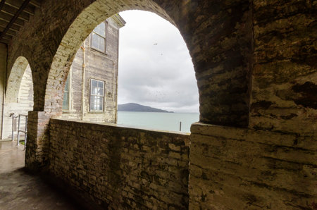 The Alcatraz Penitentiary island, now a museum, in San Francisco, California, USA. A view of the brick stone arched building and windows overlooking the Frisco Bay and Oakland from the historic federal prison.のeditorial素材