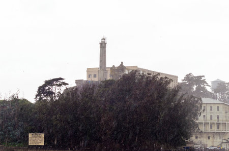 The Alcatraz Penitentiary, now a museum, in San Francisco, California, United States of America. A view of the island, the lighthouse, prison buildings and the San Francisco Bay from the coast on a rainy day.のeditorial素材