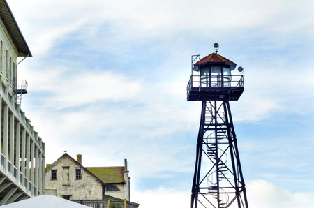 The old Guard Tower on Alcatraz Penitentiary island, now a museum, in San Francisco, California, USA. A view of the watchtower, the barracks, Building 64 and a seagull flying.のeditorial素材