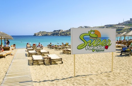 The famous Super paradise beach on the greek island Mykonos, Greece. A view of the golden sandy beach, the sign, sunbeds, umbrellas and blue sea in a perfect summer holiday party place.の写真素材