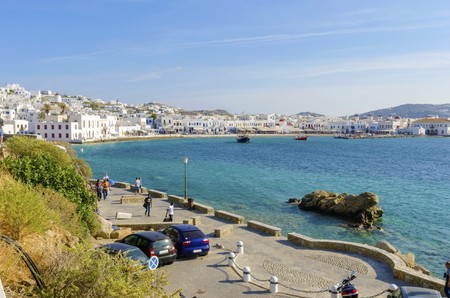 The coastline of Chora in Mykonos, Greece. Typical greek island whitewashed houses on the shore and seaview promenade overlooking the Aegean sea and calm clean blue water.の写真素材