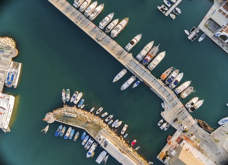 Aerial view of the beautiful Marina in Limassol city in Cyprus, the boats lined up, piers, and commercial area from above. A very modern, high end and newly developed space where yachts are moored and it's perfect for a waterfront promenade.の写真素材