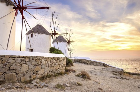 Three windmills in Chora, Mykonos, Greece at sunset. Very traditional greek whitewashed architecture, a popular landmark and tourist destination on the island of winds against the deep blue sky and the Aegean sea. The wind mills are now decorative.の写真素材