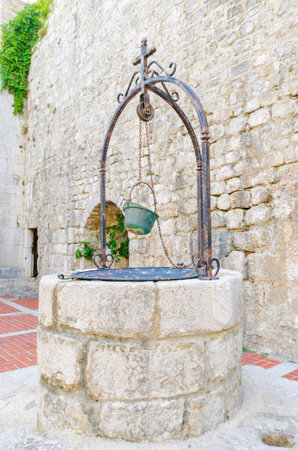 The interior of the Frankopan Castle, at Kamplin square in Krk, Croatia - Frankopanski Kastel, part of the medieval city walls. View of the well, stern with a soldier helmet as a bucketのeditorial素材