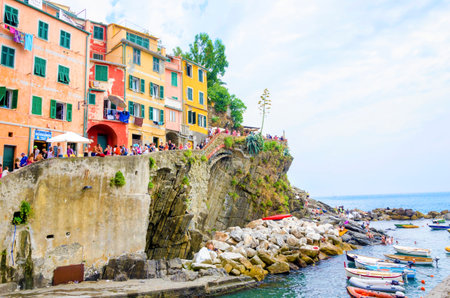 Riomaggiore village, La Spezia province, Liguria, northern Italy. View of the colourful houses on steep hills, sea rocks, beach, laundry on balconies, boats and tourists.のeditorial素材