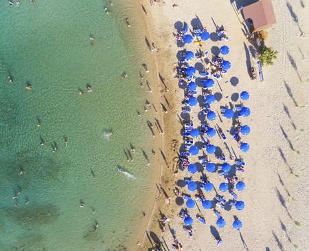 Aerial bird's eye view of sandy beach in Protaras, Famagusta, Cyprus island at the Agia Triada bay. Sun umbrellas, sea beds and silhouette of people sunbathing and swimming during the summer holiday heatの写真素材