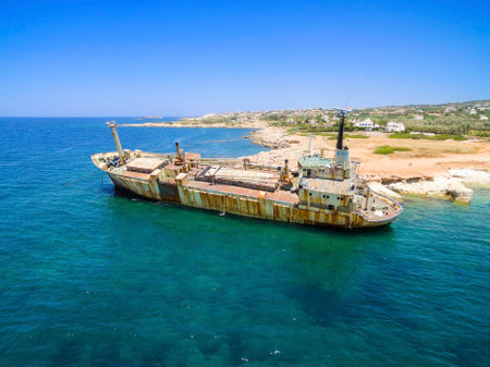 Aerial view of the abandoned ship wreck EDRO III in Pegeia, Paphos, Cyprus. The rusty shipwreck is stranded on the Peyia rocks at the kantarkastoi sea caves near Coral Bay in Pafos, standing at an angle near the shore.のeditorial素材
