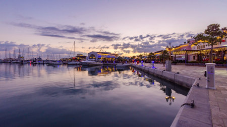 Beautiful Marina in Limassol city Cyprus at dusk. A modern, high end life and newly developed port with docked yachts, restaurants, shops, a landmark for waterfront promenade. View of the commercial area at sunset.のeditorial素材